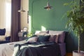 Two industrial lamps above comfortable double bed with cozy bedding, copy space on empty wall