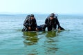 Two industrial scuba divers rescue a third diver on the lake shore. Chelyabinsk, Russia, July 2019