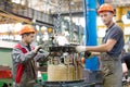 Two industrial workers assembling power transformer at conveyor factory workshop