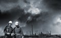 Two industry workers and distant oil refinery