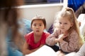 Two infant school girls sitting on bean bags in a comfortable corner of the classroom listening to their teacher reading a story, Royalty Free Stock Photo