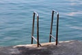 Two inox handrails for easier entrance from concrete beach to calm blue sea