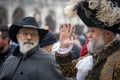 Two intelligent gray-haired aged men with a beard and mustache dressed in old style hats and suits at the carnival in Venice