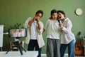 Two intercultural girls singing in microphone while boy playing harmonica