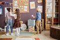 Two intercultural little girls in smart casualwear and boy with paper plane Royalty Free Stock Photo