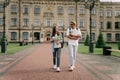 Two international stylish students walk near the campus and smile. Friendly African American guy and Caucasian girl walk Royalty Free Stock Photo
