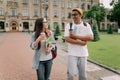 Two international stylish students walk near the campus and smile. Friendly African American guy and Caucasian girl walk Royalty Free Stock Photo