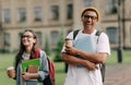 Two international stylish students walk near the campus and smile. Friendly African American guy and Caucasian girl walk Royalty Free Stock Photo