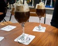 Two Irish coffees with whipped cream, dark coffee and alcoholic whisky sat on a table in a cafÃÂ© in Europe. European cafÃÂ© culture Royalty Free Stock Photo