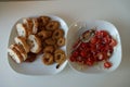 Two isolated plates with tomato and onion salad in one and bred with roasted calamaries in second one.