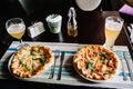 Two Italian pizza four cheese with arugula meat on brown wooden desk background on white plate. Quattro FORMAGGI. cutlery knife, Royalty Free Stock Photo