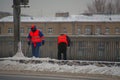 Two janitors cleaning snow on the sidewalk with shovels