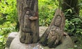 Two Japanese wood carving of a goddess and Buddha in a green forest.