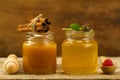 Two jars of fresh honey with cinnamon, flowers, raspberries on wooden background