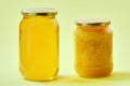 Two jars of honey isolated on a yellow background. One crystallized. Royalty Free Stock Photo