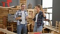 Two jaunty carpenters, a man and woman, dancing and drilling to music at their lively furniture carpentry business workplace