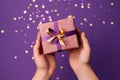 two joined hands holding a golden gift box with glittering ribbons, symbolizing gratitude and affection, human connection through