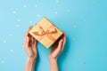 two joined hands holding a golden gift box with glittering ribbons, symbolizing gratitude and affection, human connection through