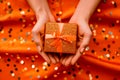 two joined hands holding a golden gift box with glittering ribbons, symbolizing gratitude and affection, human connection through