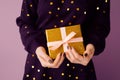 two joined hands holding a golden gift box with glittering ribbons, symbolizing gratitude and affection, human connection through