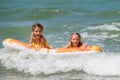 Two joyful girls ride on a water mattress on the sea waves.