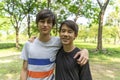 Two joyful teenage boys in the summer park against the blue sky.