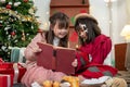 Two joyful young Asian girls are enjoying reading a Christmas fairy tale story in a book together Royalty Free Stock Photo