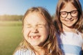 Two joyfull girls hugging and closed their eyes from the sun.