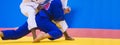 Two judo fighters in white and blue uniform