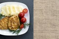 Two juicy fried meat patties on a white plate with cherry tomatoes Royalty Free Stock Photo