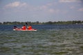 Two kayakers in orange vests are driving a kayak on the lake