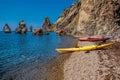 Two kayaks on an isolated rocky beach, against the background of a cliff in the sea. Kayaking along the coast of the island near Royalty Free Stock Photo