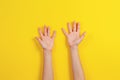 Two kid arms on yellow background. Top view to empty opened palms up. Hands gesture Royalty Free Stock Photo