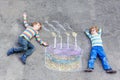Two kid boys having fun with colorful birthday cake drawing with