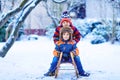 Two kid boys having fun sleigh ride during snowfall. Children sledding on snow. siblings riding a sledge. Twins play