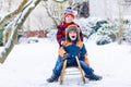 Two kid boys having fun sleigh ride during snowfall. Children sledding on snow. siblings riding a sledge. Twins play Royalty Free Stock Photo