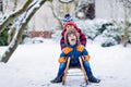 Two kid boys having fun sleigh ride during snowfall. Children sledding on snow. siblings riding a sledge. Twins play Royalty Free Stock Photo