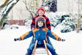 Two kid boys having fun sleigh ride during snowfall. Children sledding on snow. siblings riding a sledge. Twins play Royalty Free Stock Photo