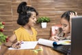 Two kid siblings busy in talking during e-learning or online class - concept of homeschooling or remote classroom at home during