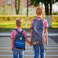 Two kids with backpacks walking on the road, holding. School time Royalty Free Stock Photo