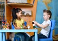 Two kids boy and girl sit at the table and play toy doctors