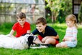 Two kids boys and little toddler girl playing with family dog in garden. Three children, adorable siblings having fun Royalty Free Stock Photo