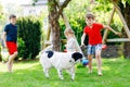 Two kids boys and little toddler girl playing with family dog in garden. Three children, adorable siblings having fun Royalty Free Stock Photo