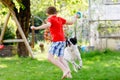 Two kids boys playing with family dog in garden. Laughing children, adorable siblings having fun with dog, with running Royalty Free Stock Photo