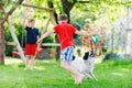 Two kids boys playing with family dog in garden. Laughing children, adorable siblings having fun with dog, with running Royalty Free Stock Photo