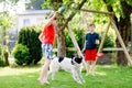 Two kids boys playing with family dog in garden. Laughing children, adorable siblings having fun with dog, with running Royalty Free Stock Photo