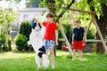 Two kids boys playing with family dog in garden. Laughing children, adorable siblings having fun with dog, with running Royalty Free Stock Photo