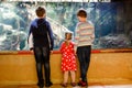 Two kids boys and toddler girl visiting together zoo aquarium. Three children watching fishes and jellyfishes. School Royalty Free Stock Photo