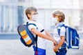 Two kids boys wearing medical mask on the way to school. Children with satchels. Schoolkids on warm sunny day. Lockdown Royalty Free Stock Photo