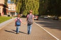 Two kids brothers with backpack holding on hands walking to school. Back view. Royalty Free Stock Photo